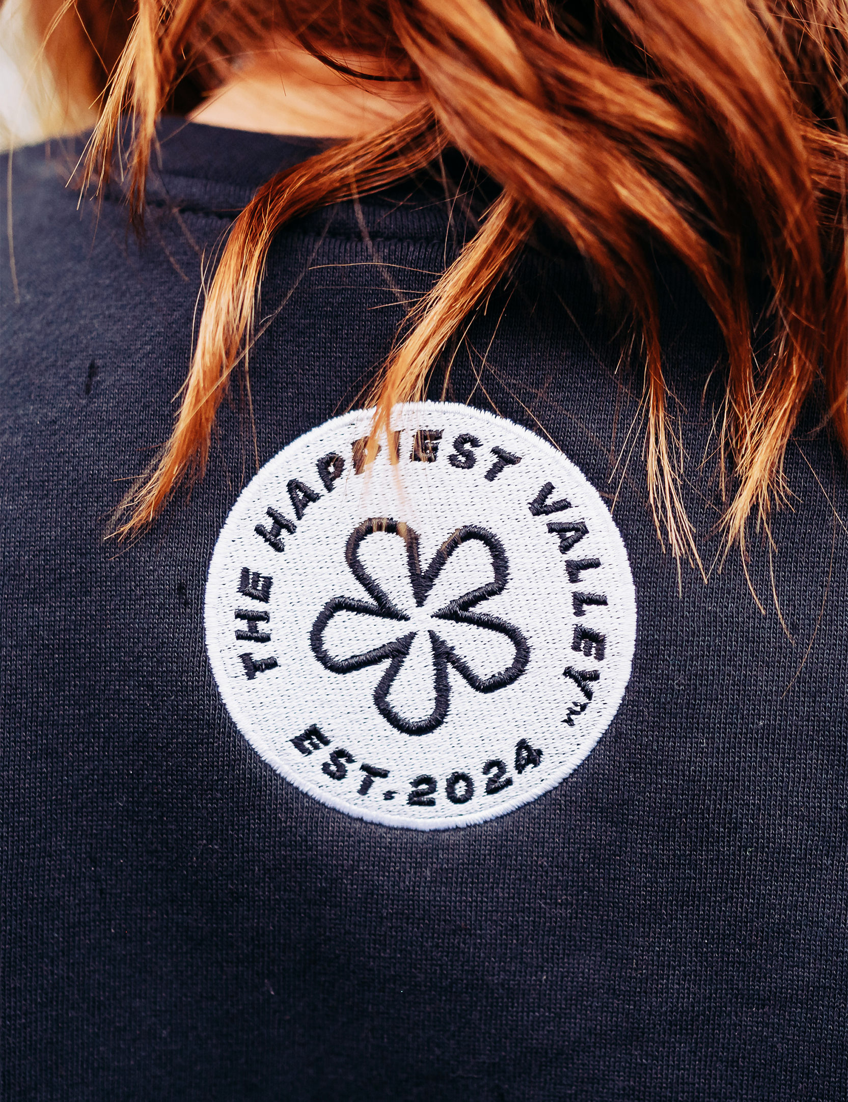 https://bonafidephoto.com Photo of @happyvalleyhannah wearing navy crew neck sweater with white embroidered badge logo 'the happiest valley, established 2024' Perfect for Penn State fans and nostalgia for good times in happy valley / State College, PA