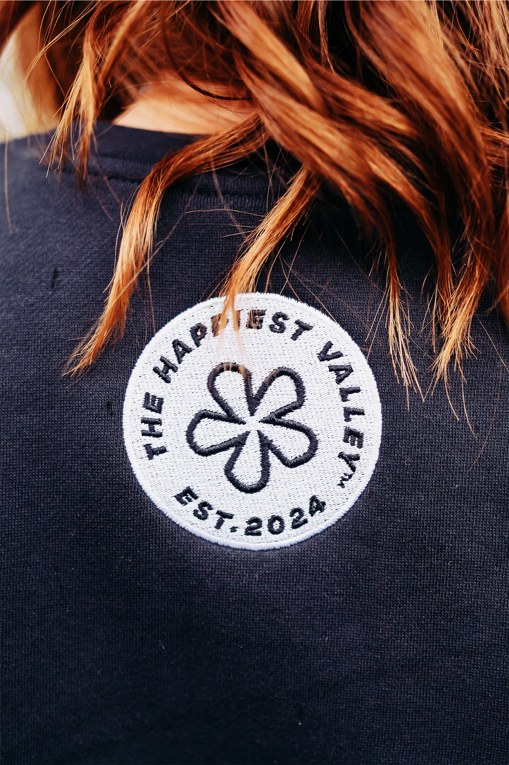 https://bonafidephoto.com Photo of @happyvalleyhannah wearing navy crew neck sweater with white embroidered badge logo 'the happiest valley, established 2024' Perfect for Penn State fans and nostalgia for good times in happy valley / State College, PA
